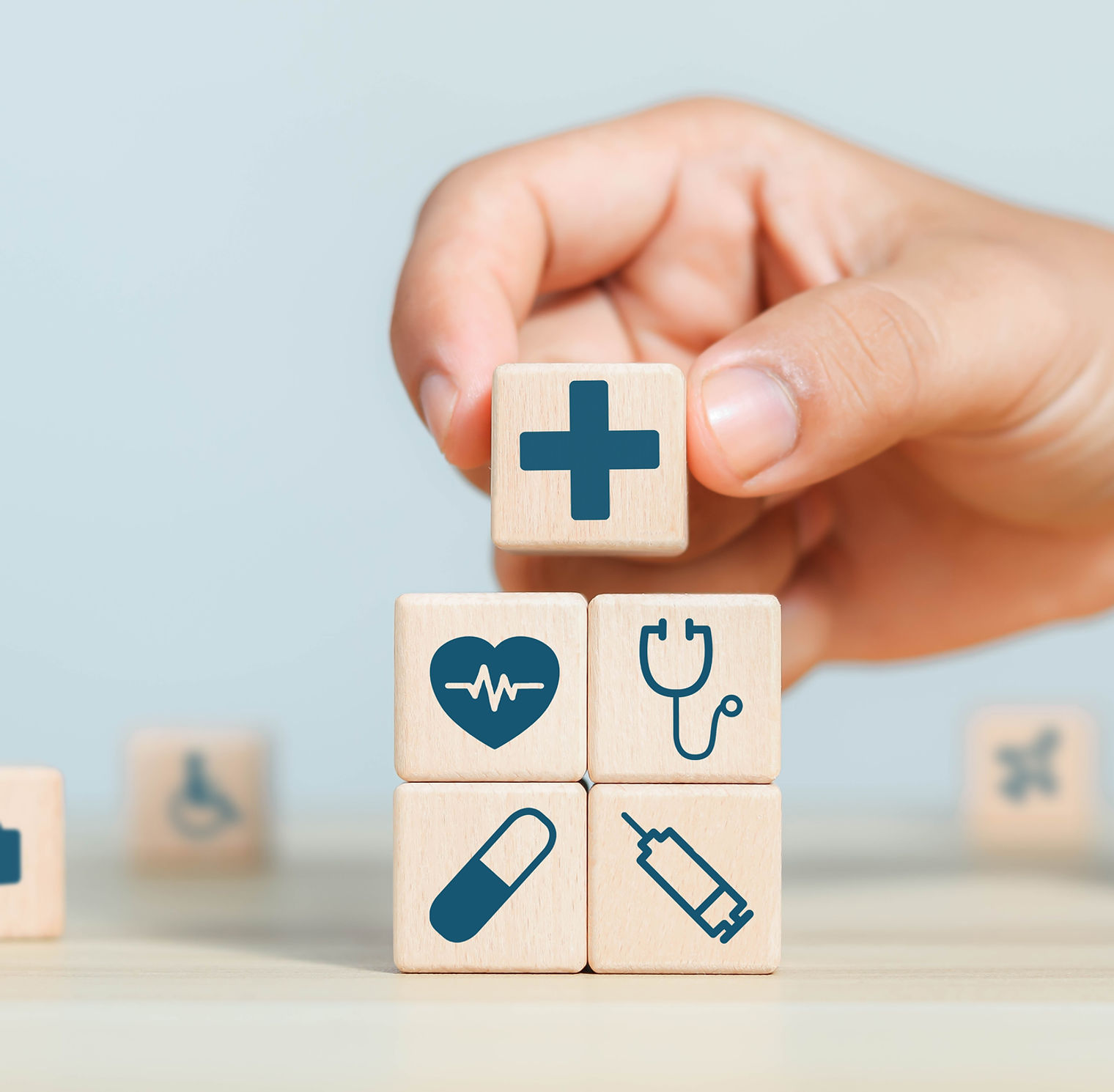 Hand arranging wooden blocks with medical icons